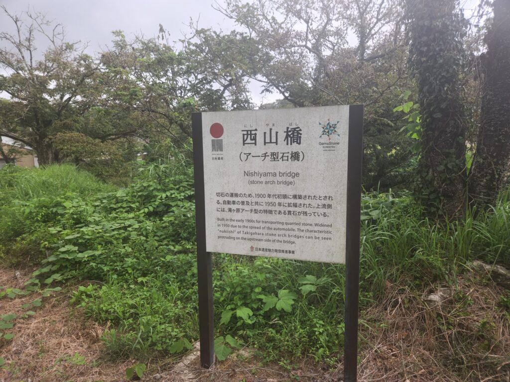 西山橋の案内板。1900年代初頭、1950年に拡幅、上流側に貫石