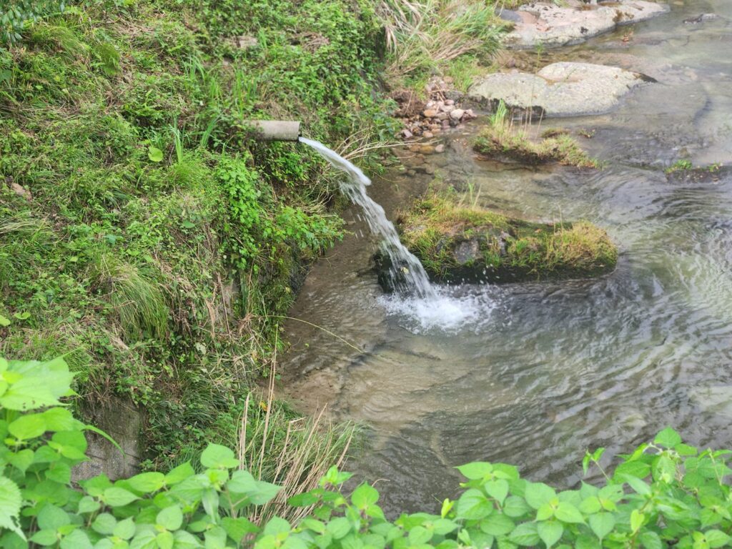 岸から突き出したパイプから、川へ水が落ちている